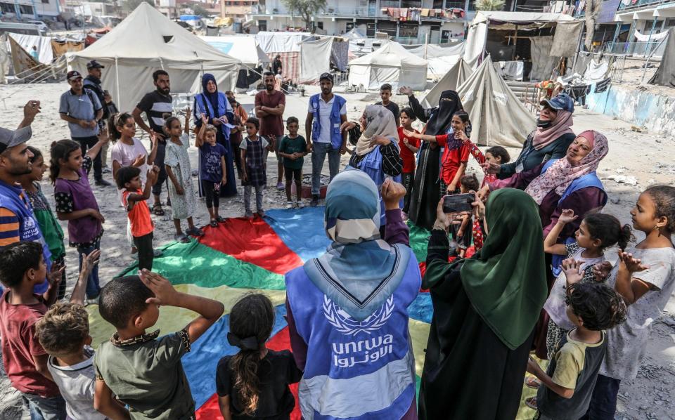 Officials of United Nations Relief and Works Agency for Palestine Refugees in the Near East (UNRWA) play with the children who were adversely affected by Israeli attacks