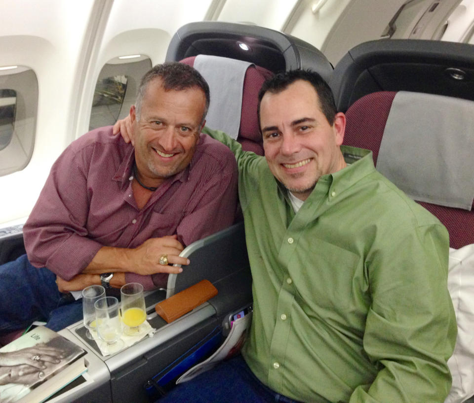 In a March 2014 photo provided by Dale Scott, Major League Baseball umpire Dale Scott, left, sits with his spouse Michael Rausch on a plane going to Australia. Scott disclosed that he is gay and that he and Raklusch married in November of 2013. (AP Photo/ released by Dale Scott)