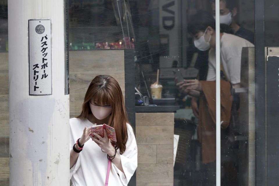 A woman wearing a protective mask to help curb the spread of the coronavirus looks at a mobile phone at Shibuya district Thursday, Sept. 30, 2021, in Tokyo. Fumio Kishida, the man soon to become Japan’s next prime minister, says he believes raising incomes is the only way to get the world’s third-largest economy growing again. Top of Kishida’s to-do list is another big dose of government spending to help Japan recover from the COVID-19 shock. (AP Photo/Eugene Hoshiko)