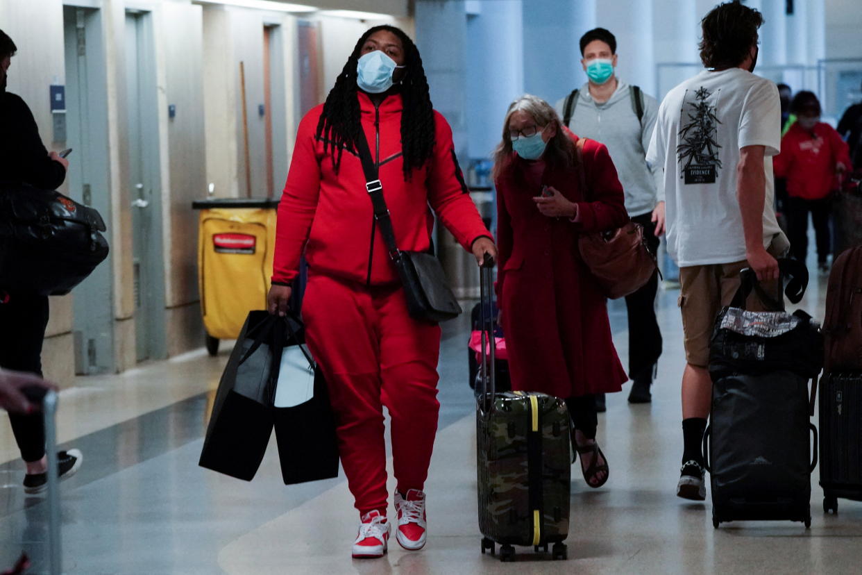 Travelers carrying luggage walk through a terminal at Los Angeles International Airport (LAX) during the holiday season as the coronavirus disease (COVID-19) Omicron variant threatens to increase case numbers in Los Angeles, California, U.S., December 22, 2021. REUTERS/Bing Guan