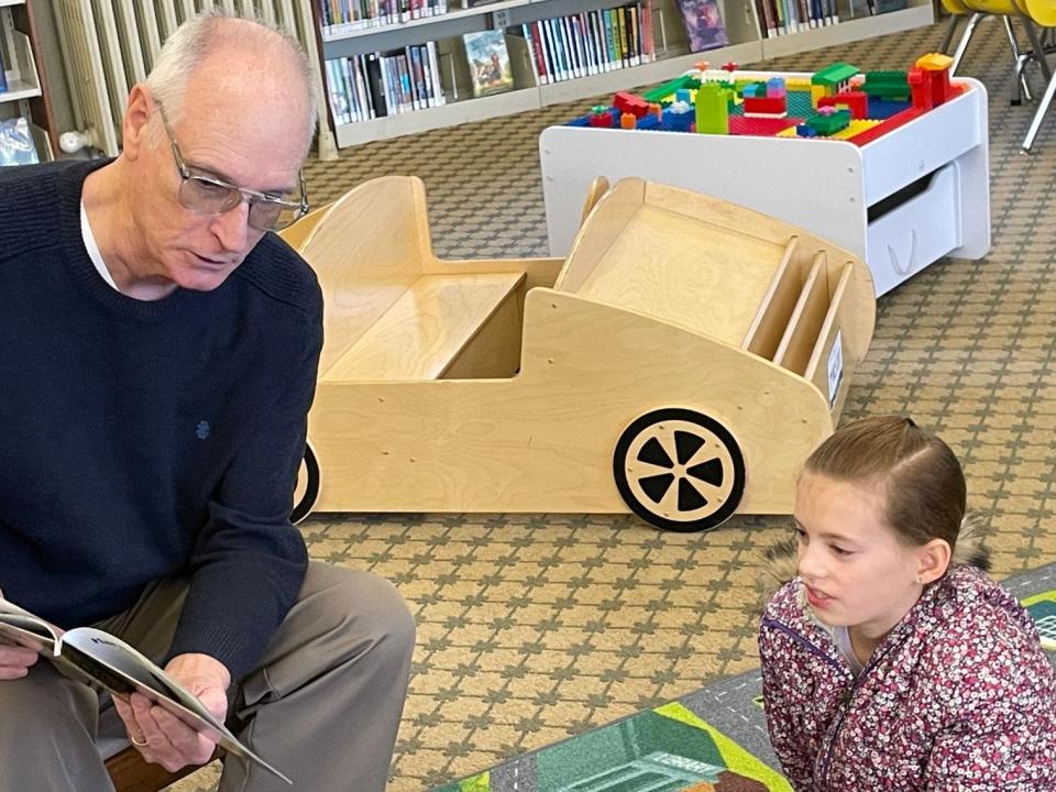 Retired professor William McCloskey reads the children’s book “Harriet Tubman" to Lindsay Young, 10, Saturday at Dorsch.