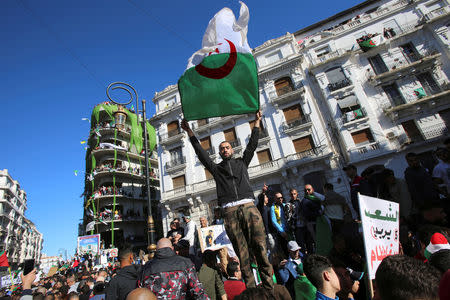 FILE PHOTO: A demonstrator carries a national flag during protest over President Abdelaziz Bouteflika's decision to postpone elections and extend his fourth term in office, in Algiers, Algeria March 15, 2019. REUTERS/Ramzi Boudina/File Photo