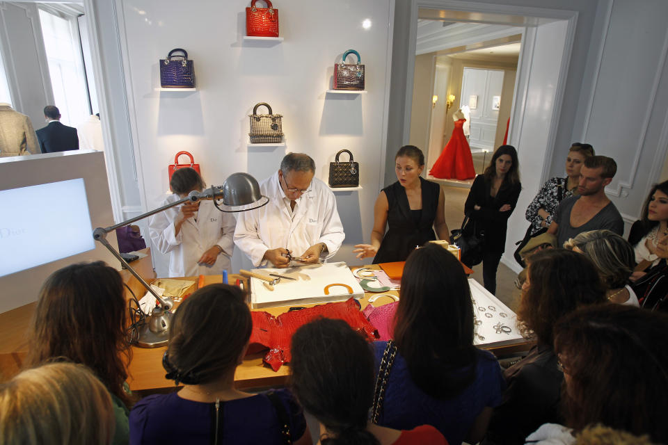 Members of the media and guests are gathered around a trunk maker at the Dior fashion house in Paris, Friday June 14, 2013, as part of the Les Journees Particulieres, event organised for two days by LVMH group. More than forty LVMH group locations throughout Europe are opening their doors and inviting the public to discover the savoir-faire of the luxury fashion industry group, for a two day open-door event. (AP Photo/Remy de la Mauviniere)