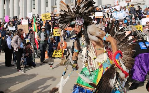 A supporter of the Bears Ears and Grand Staircase-Escalante National Monuments dances with a headdress during a rally Saturday - Credit: AP