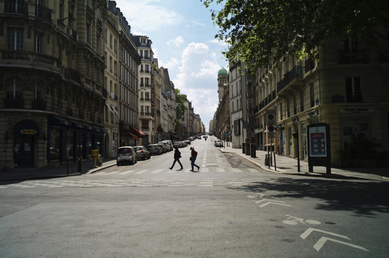 People cross a deserted street during nationwide confinement measures to counter the Covid-19, in Paris, Monday, April 27, 2020. France continues to be under an extended stay-at-home order until May 11 in an attempt to slow the spread of the COVID-19 pandemic. (AP Photo/Thibault Camus)