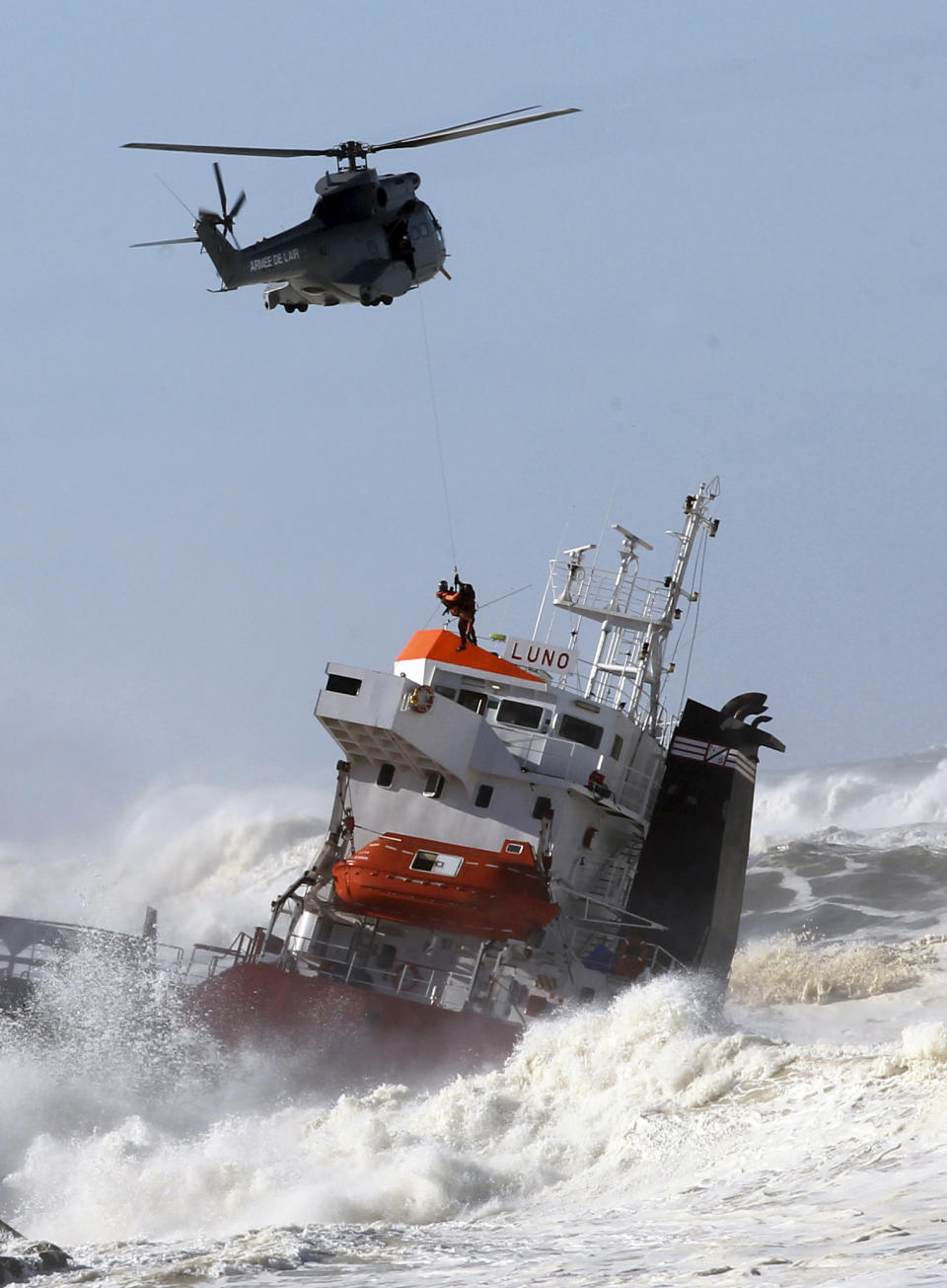 A sailor is helped lifted off by a military helipcopter after a Spanish cargo ship that slammed into a jetty in choppy Atlantic Ocean waters off Anglet, southwestern France, Wednesday, Feb. 5, 2014. The hold of the ship, the Luno, was empty when the accident occurred along the coast of the town of Anglet, and a small amount of fuel was spilling into the water, officials said. The ship had been heading to a nearby port to load up with cargo when its engine conked out and the rough waves carried it into the jetty. (AP Photo/Bob Edme)