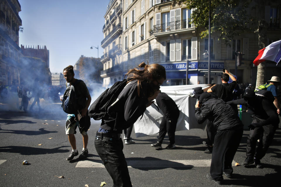 Protestors protect themselves from teargas during a climate demonstration, in Paris, Saturday, Sept. 21, 2019. Scuffles broke out in Paris between some violent activists and police which responded with tear gas at a march for climate gathering thousands of people in Paris. (AP Photo/Thibault Camus)