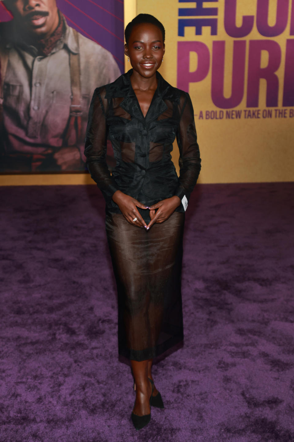 Lupita in a mid-calf sheer black skirt and long-sleeved sheer black blouse