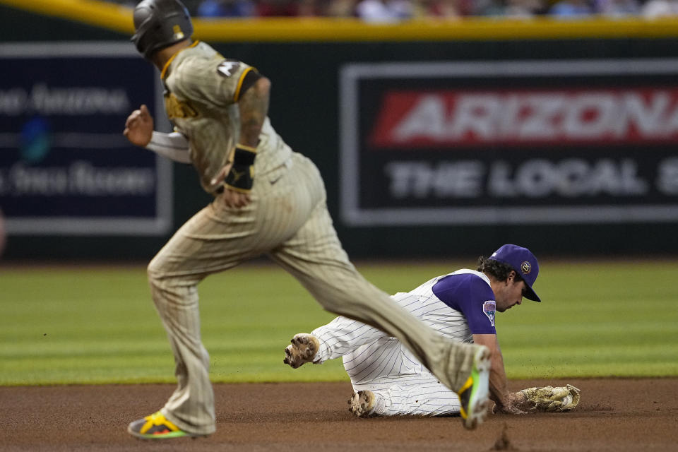 Arizona Diamondbacks' Buddy Kennedy stops a base hit by San Diego Padres' Jake Cronenworth from leaving the infield as Padres' Manny Manchado advance to third during the fourth inning of a baseball game, Saturday, Aug. 12, 2023, in Phoenix. (AP Photo/Matt York)