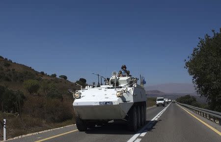 A member of the U.N. Disengagement Observer Force (UNDOF) rides atop an armoured vehicle near the Quneitra border crossing on the Israeli-occupied Golan Heights August 28, 2014. REUTERS/Ronen Zvulun