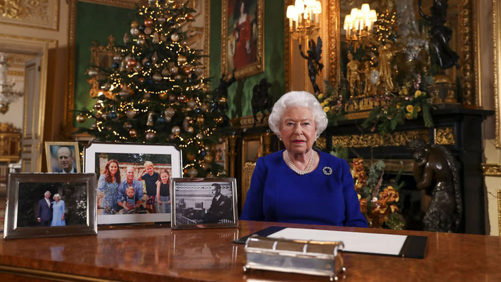 Queen Elizabeth II during her annual Christmas speech in her study with pictures of the royal family arranged on the desk