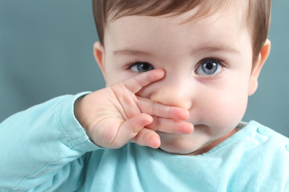 Close up of a baby girl looking at camera with a big blue eyes with a green unfocused background