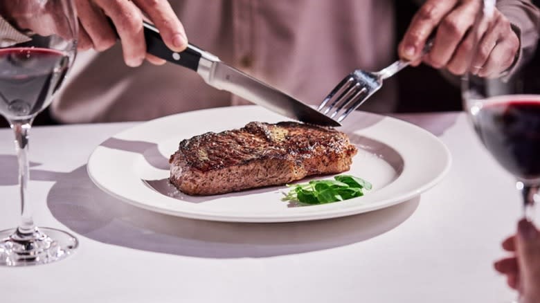 Person cutting Capital Grille steak