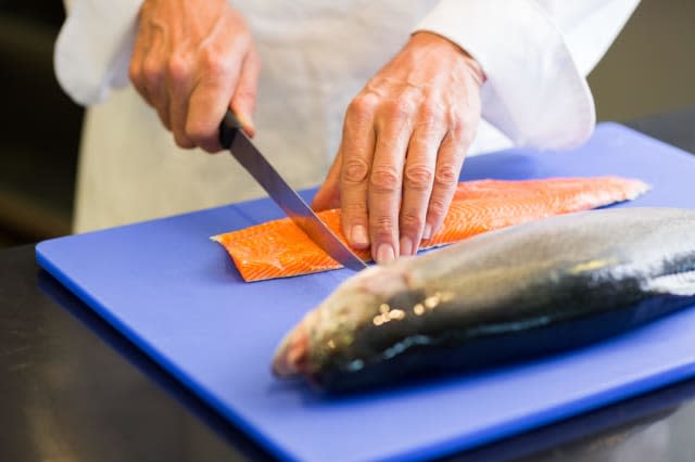 Closeup mid section of a chef cutting fish