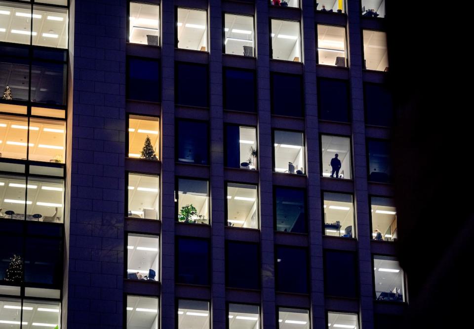 A man looks out of the window of an office building in Frankfurt, Germany, Dec. 6, 2022. A new report says climate commitments by companies aren’t always as green as they seem. The report published Monday, Feb. 13, 2023, concludes that major brands are exaggerating how ambitious their efforts to cut greenhouse gas emissions are, essentially misleading consumers, investors and governments.