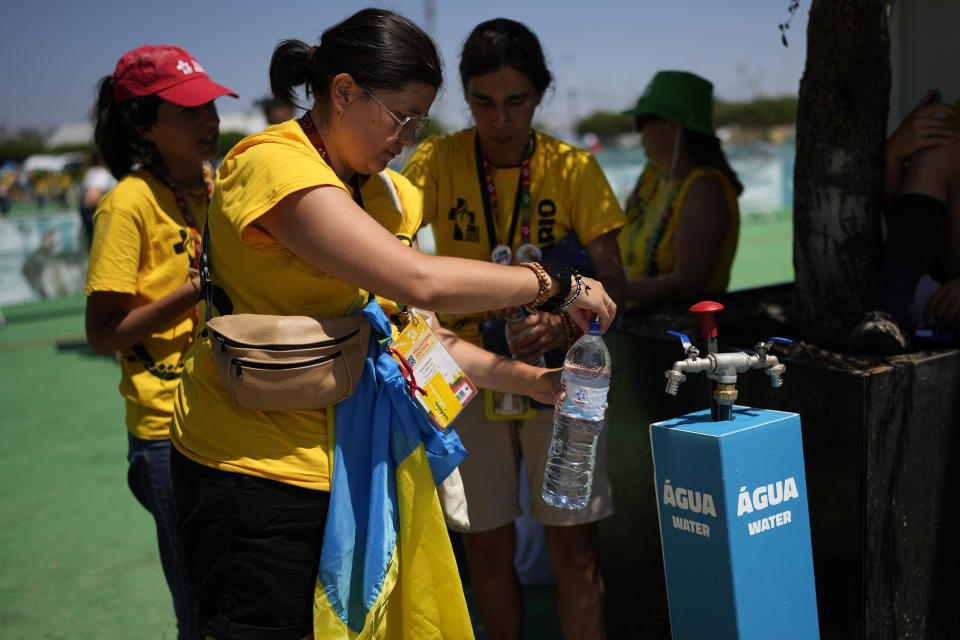 World Youth Day volunteers fill their bottles with water ahead of the Pope Francis arrival at Passeio Marítimo in Algés, just outside Lisbon, Sunday, Aug. 6, 2023. Pope Francis told young people on Sunday the Catholic Church needs them and urged them to follow their dreams as he wrapped up World Youth Day in Portugal with a massive open-air Mass and an announcement that the next edition would be held in Asia for the first time in three decades. (AP Photo/Armando Franca)