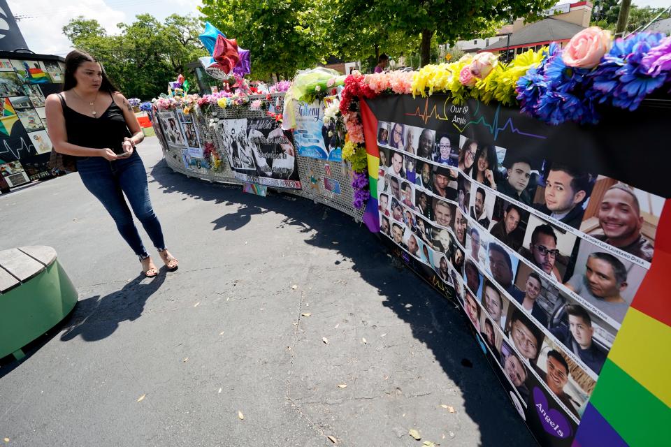 A visitor looks over a display with the photos and names of the 49 victims that died at the Pulse nightclub in Orlando, Fla., in 2016.