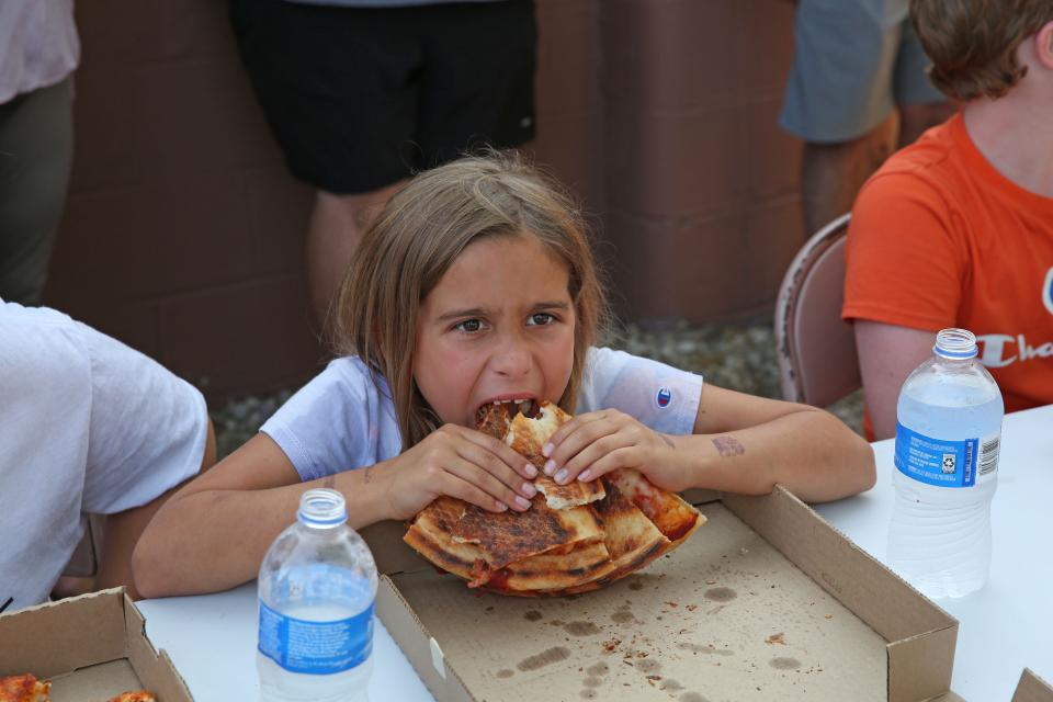 Kailyn Watson, 8, of Genoa, stacks up several pieces of pizza in the Oggie's Pizza Eating Contest, at the Gibsonburg Homecoming Festival on Wednesday night.