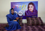 Female Afghan parliamentary election candidate, Dewa Niazai, sits in front of her poster during an election campaign in Jalalabad, Afghanistan October 3, 2018. REUTERS/Parwiz