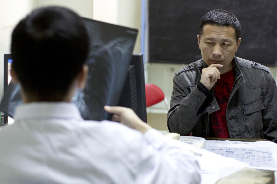 In this April 9, 2014 photo, lawyer Tang Jitian waits in an emergency room as a doctor checks his X-ray photo at a hospital in Beijing. Tang is among a group of four Chinese rights lawyers who allege they were tortured by police after being rounded up in late March outside a detention center in a farming community on the northeastern edge of China. (AP Photo/Alexander F. Yuan)