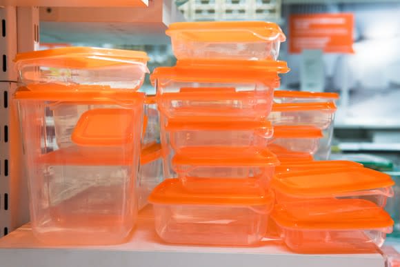 Stacks of multiple plastic tupperware containers with orange lids.