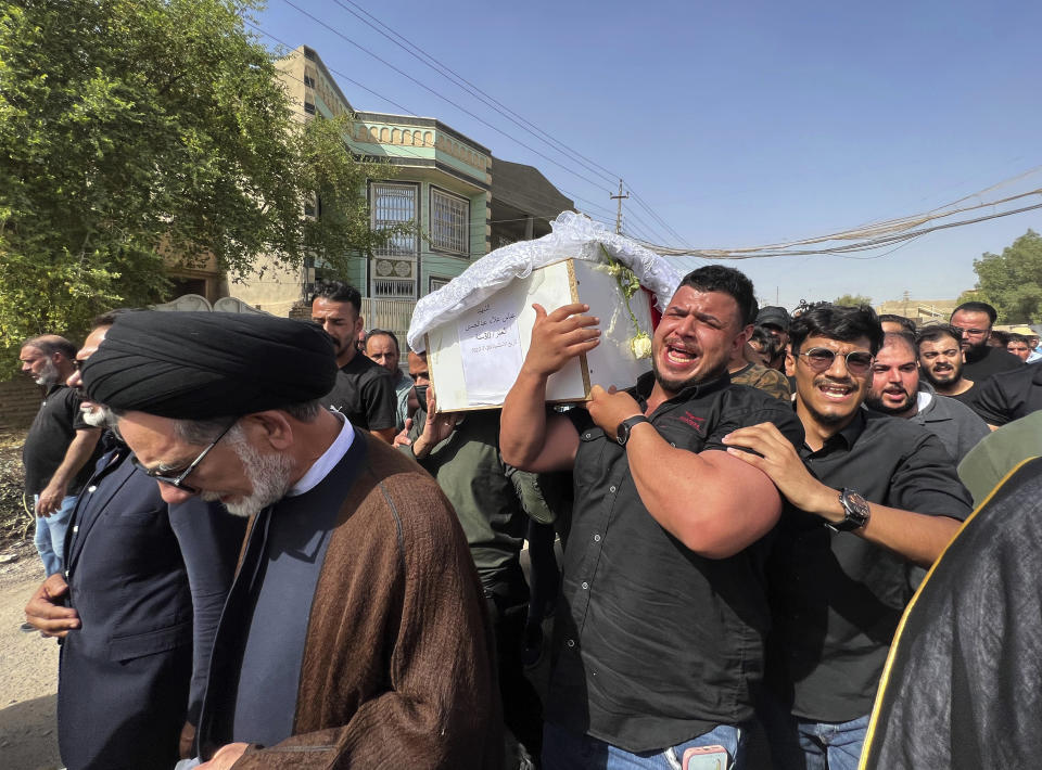 The coffin carrying Abbas Abdul Hussein, a 30-year-old victim of an artillery strike, is received by his family in Baghdad, to later lay him to rest in Najaf city, Thursday, July 21, 2022, in Baghdad, Iraq. Hussein was on his honeymoon, five days after his wedding, when at least four artillery shells struck the resort area of Barakh in the Zakho district in the Iraqi semi-autonomous Kurdish-run region, killing nine people. (AP Photo/Ali Jabar)