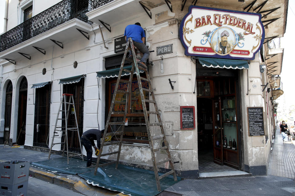 Men work on the facade of the El Federal Bar in Buenos Aires, Argentina, Tuesday, Nov. 10, 2020. Overall, about 2,000 bars, restaurants and cafes have closed in Argentina’s capital since the lockdown caused by the new coronavirus pandemic. (AP Photo/Natacha Pisarenko)