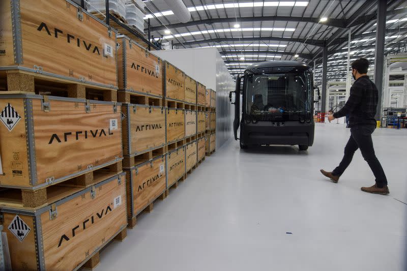 A person walks near a prototype of fully-electric van made by electric van and bus maker Arrival Ltd, in Banbury