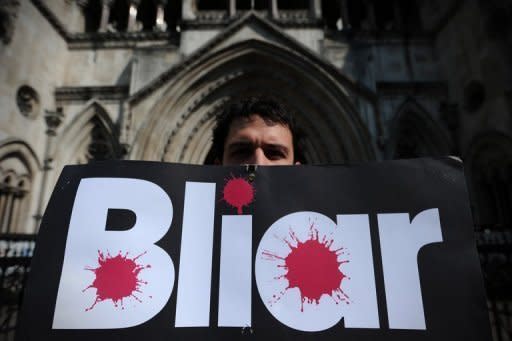 A protester holds a placard bearing the slogan "Bliar" as he demonstrates outside the High Court as former British premier Tony Blair gives evidence to the Leveson Inquiry into media ethics