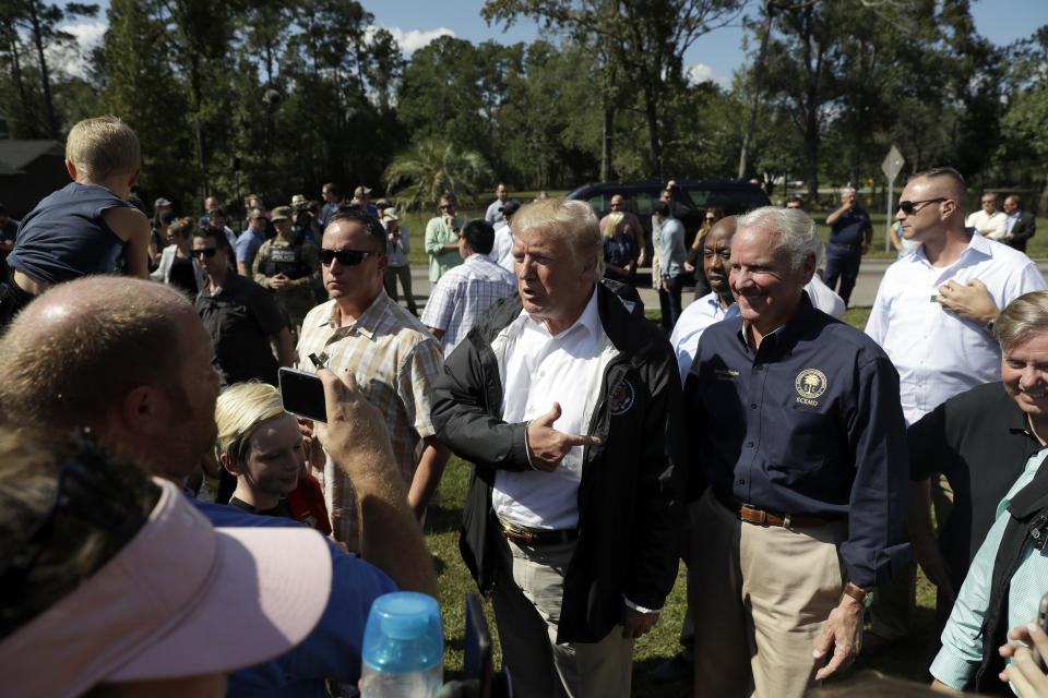 President Donald Trump visits a neighborhood impacted by Hurricane Florence, Wednesday, Sept. 19, 2018, in Conway, S.C., accompanied by South Carolina Gov. Henry McMaster and Sen. Lindsey Graham, R-S.C., right. (AP Photo/Evan Vucci)