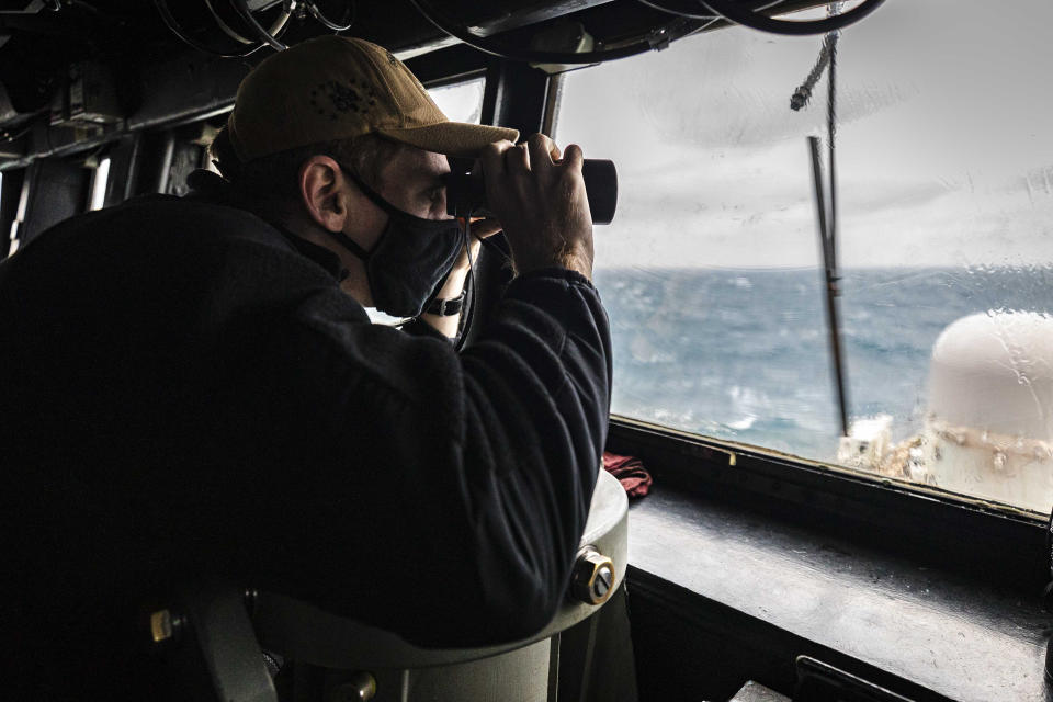 In this Dec. 30, 2020, file photo provided by U.S. Navy, Ensign Grayson Sigler, from Corpus Christi, TX., scans the horizon while standing watch in the pilot house as guided-missile destroyer USS John S. McCain conducts routine underway operations in support of stability and security for a free and open Indo-Pacific, at the Taiwan Strait. As China flexes its muscle in the Taiwan Strait and the Asia-Pacific region, Taiwan has become a regional flashpoint, as Japan, the United States and other democracies develop closer ties with the self-ruled island that Beijing regards as a renegade territory to be united by force if necessary. (Mass Communication Specialist 2nd Class Markus Castaneda/U.S. Navy via AP, File)
