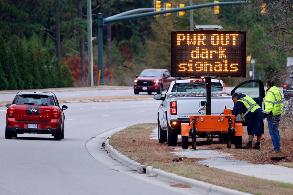 Workers set up an automated display warning drivers on NC211 of the power outage in the area and how to approach the upcoming intersections in Southern Pines, N.C., Monday, Dec. 5, 2022.<span class="copyright">Karl B DeBlaker—AP</span>