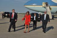 <p>The first lady matched her $2,095 red Givenchy cape dress with $595 Christian Louboutin flats to greet her husband and well-wishers at the airport. (Photo: Getty Images) </p>