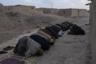 Taliban fighters and Afghan men pray in Kamar Kalagh village near Herat, Afghanistan, Saturday, Nov. 27, 2021. Afghanistan’s drought, its worst in decades, is now entering its second year, exacerbated by climate change. (AP Photo/Petros Giannakouris)