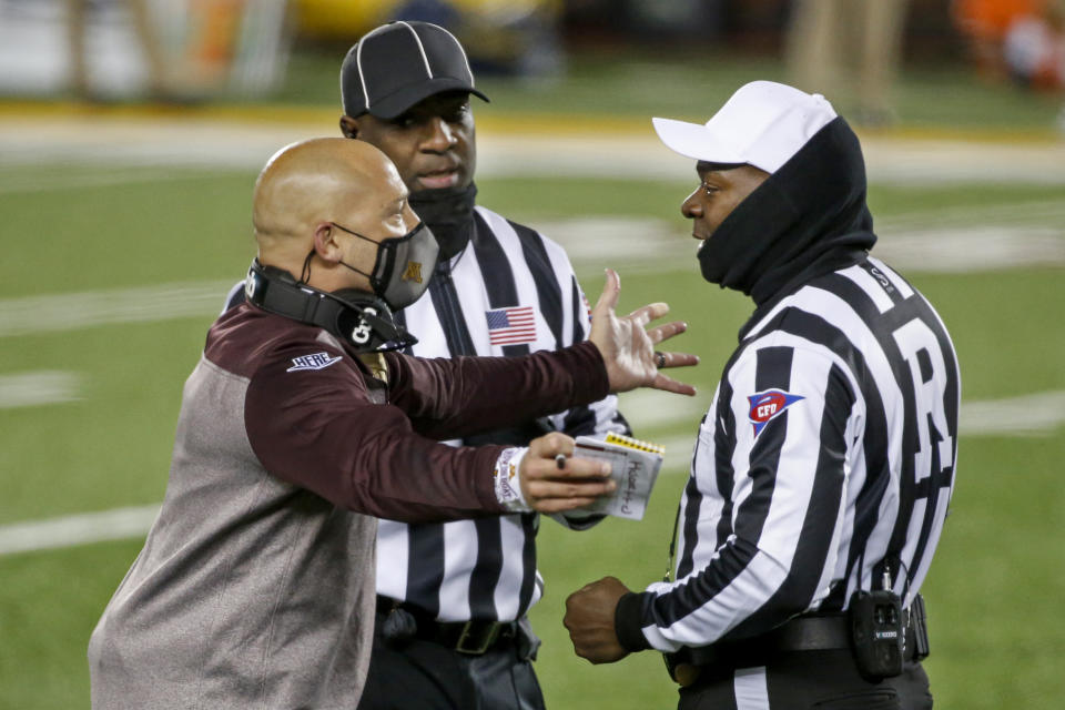 Minnesota head coach P.J. Fleck has a discussion with referee Larry Smith and headline judge William McKoy during a break in action at an NCAA college football game with Michigan Saturday, Oct. 24, 2020, in Minneapolis. (AP Photo/Bruce Kluckhohn)