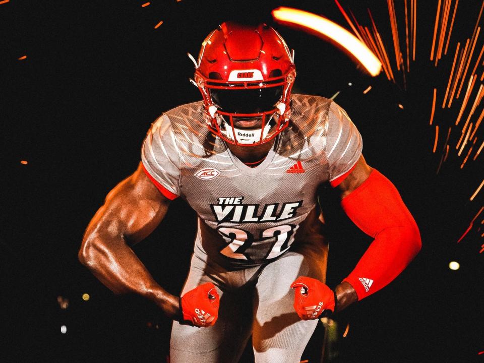 A Louisville Cardinals football player flexes in a promo for a new grey-based uniform.