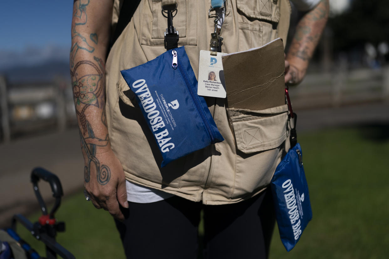 Kelly Richardson, a mental health case manager from the People Concern, a social services agency based in Los Angeles County, talks to a homeless person while carrying pouches containing Narcan nasal spray kits in Santa Monica, Calif., Monday, Sept. 19, 2022. (AP Photo/Jae C. Hong)