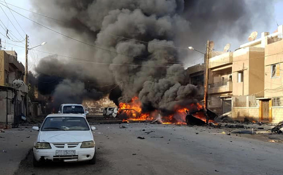 This photo by Hawar news, the news agency for the semi-autonomous Kurdish areas in Syria (ANHA), shows flames rising from burned cars at the site of an explosion in the central Qamishli city in northeastern Syria, Friday, Oct. 11, 2019. Activists and Syrian Kurdish officials are reporting a large explosion outside a popular fast food restaurant. It was not clear what caused the explosion on Friday which occurred amid intensive shelling by the Turkish military in the city and other areas. (ANHA via AP)