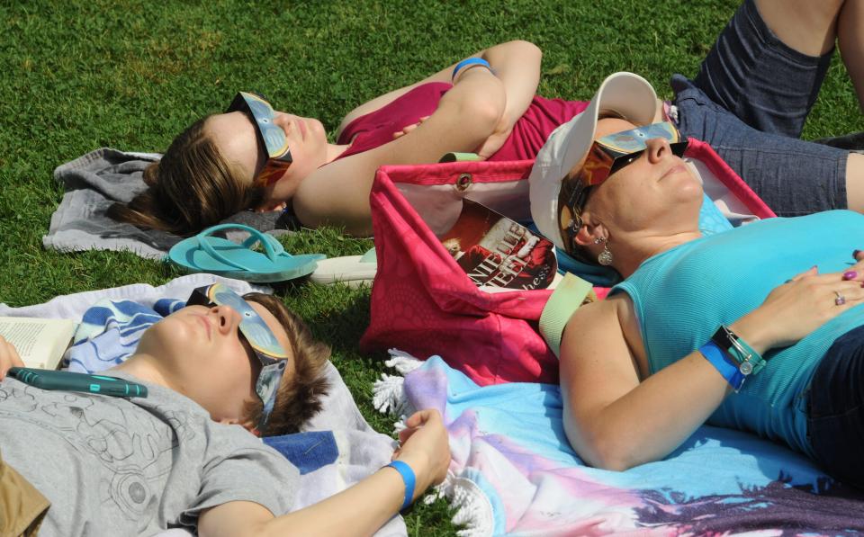 A mother watches the solar eclipse where her two children in 2017 in Massachusetts. The glasses they're wearing are highly recommended for skygazers who want to avoid damaging their retinas during Monday's celestial event.