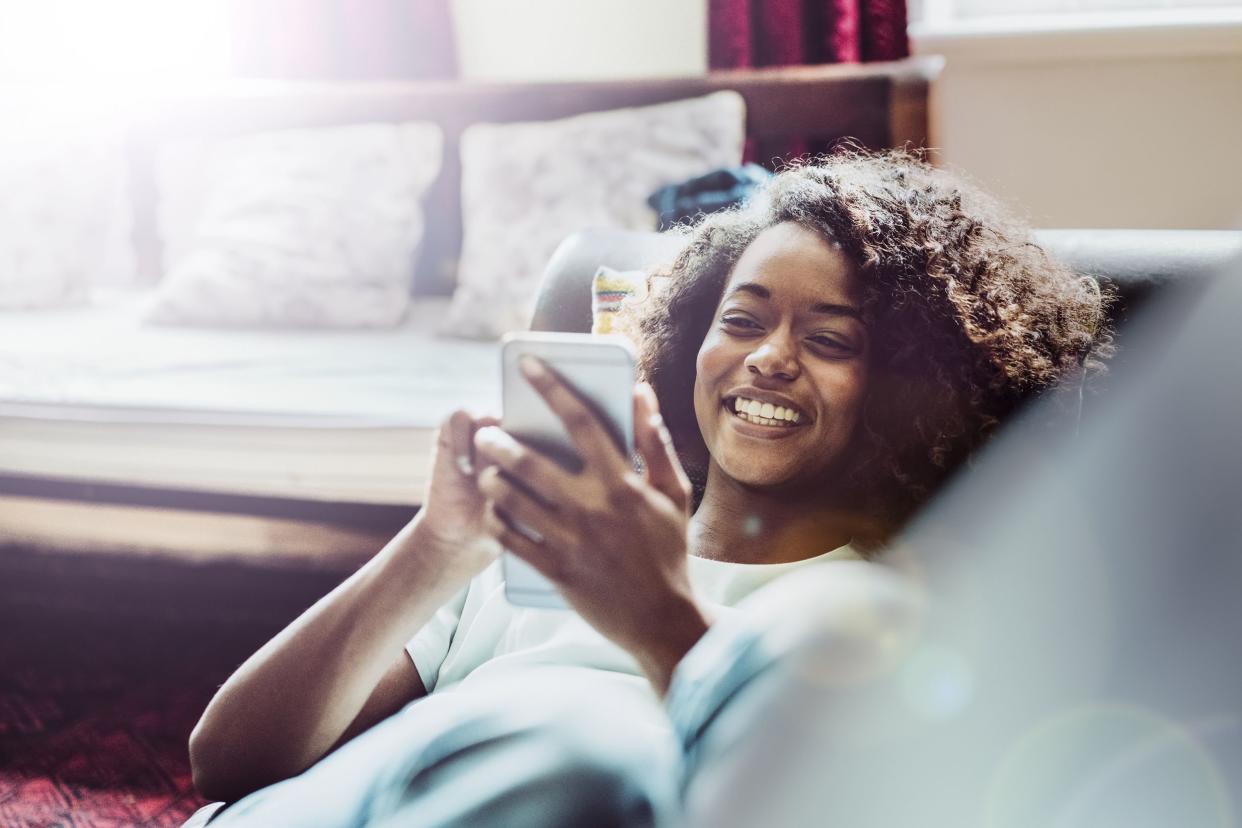 happy woman using mobile phone on sofa