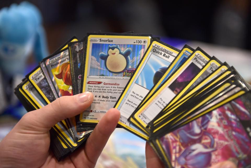 Pokemon cards, including a Snorlax, are seen spread out in a hand.