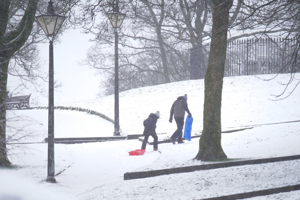 People carry sleds up a hill in the Pavilion Gardens (PA)