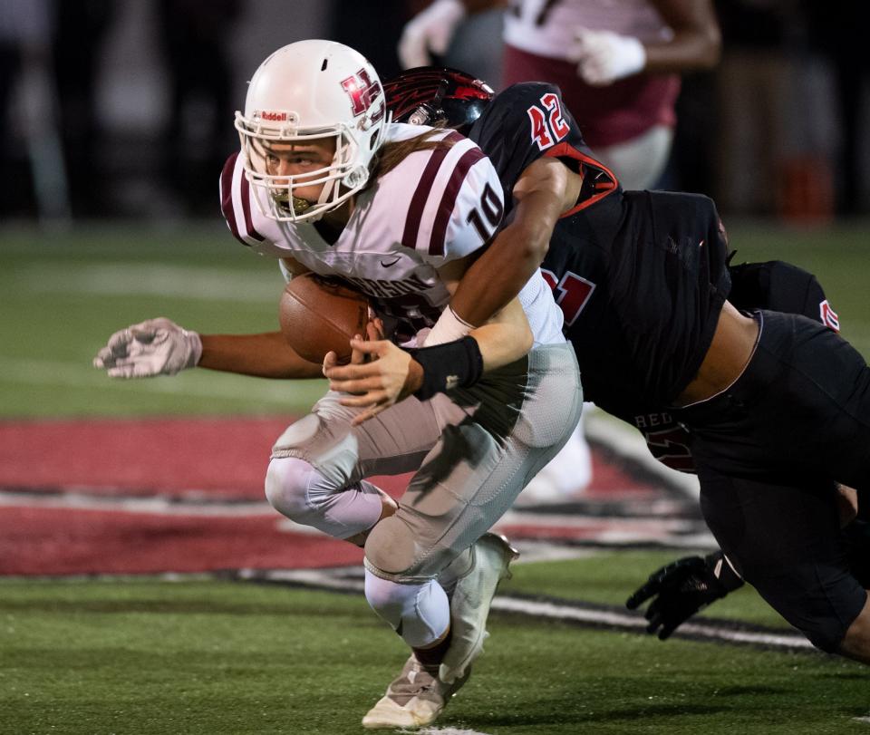 Henderson's Seth Goben (10) gets tackled by Owensboro's Kanye Johnson (42) during the football game between the Henderson County Colonels and the Owensboro Red Devils at Rash Stadium in Owensboro, Ky., Friday evening, Oct. 29, 2021. 