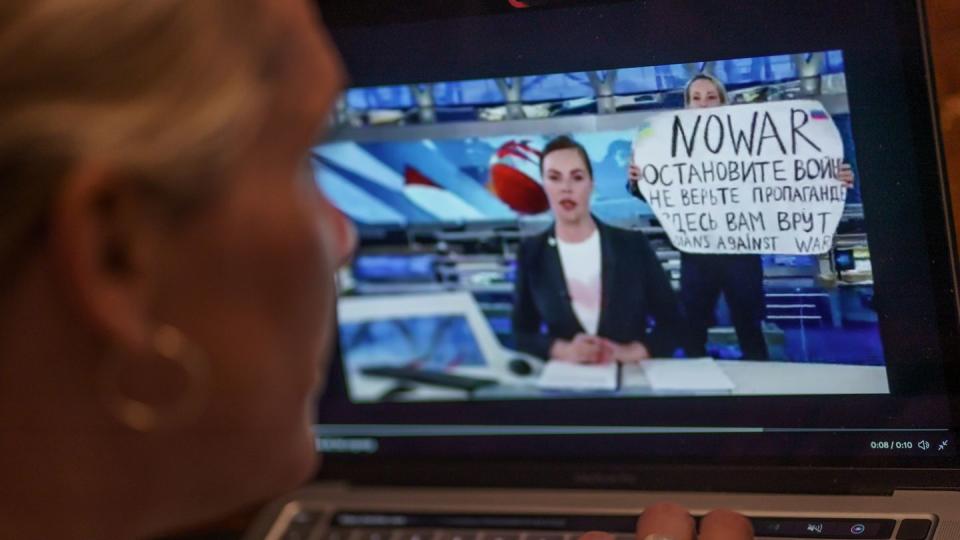 Eine Mitarbeiterin des russischen Staatsfernsehens stört mit einem Protestplakat eine Nachrichtensendung