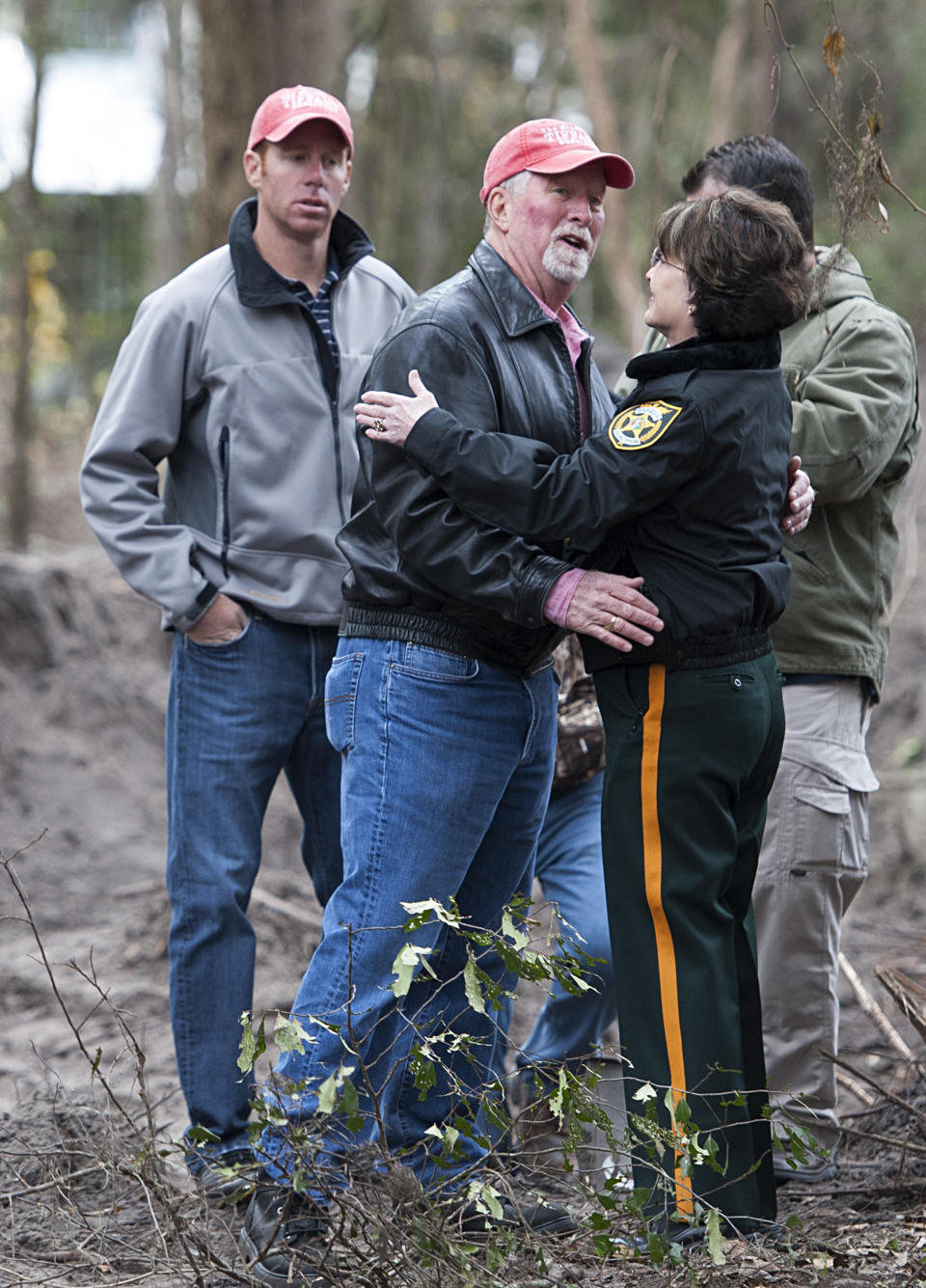 Alachua County Sheriff Sadie Darnell, right, embraces Patrick Sessions, the father of missing University of Florida student Tiffany, who disappeared in 1989 as Tiffany's brother Jason, left, looks on Thursday, Feb. 6, 2014 in Gainesville, Fla. Darnell announced that Paul Rowles, a serial killer who died in prison last year, has been named as a suspect in the disappearance of Tiffany. (AP Photo/Phil Sandlin)