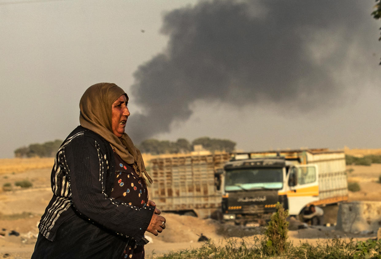 A woman walks as smoke billows following Turkish bombardment in Syria's northeastern town of Ras al-Ain in the Hasakeh province along the Turkish border on October 9, 2019. (Photo: Delil Souleiman /AFP via Getty Images)