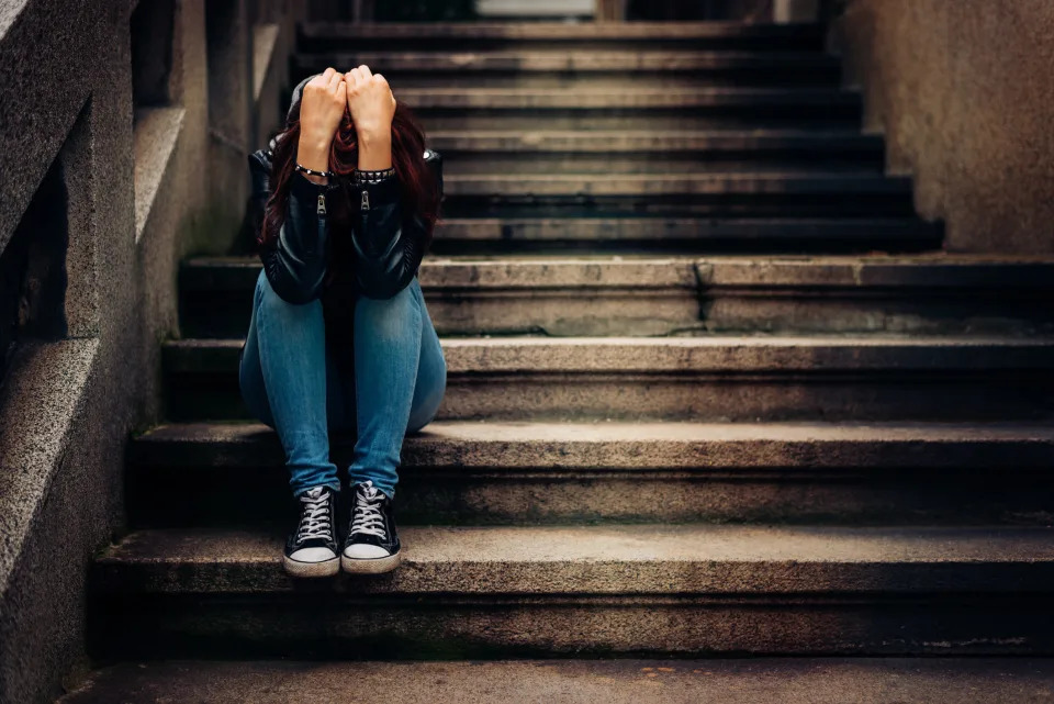 someone sitting on stairs with their head behind their arms