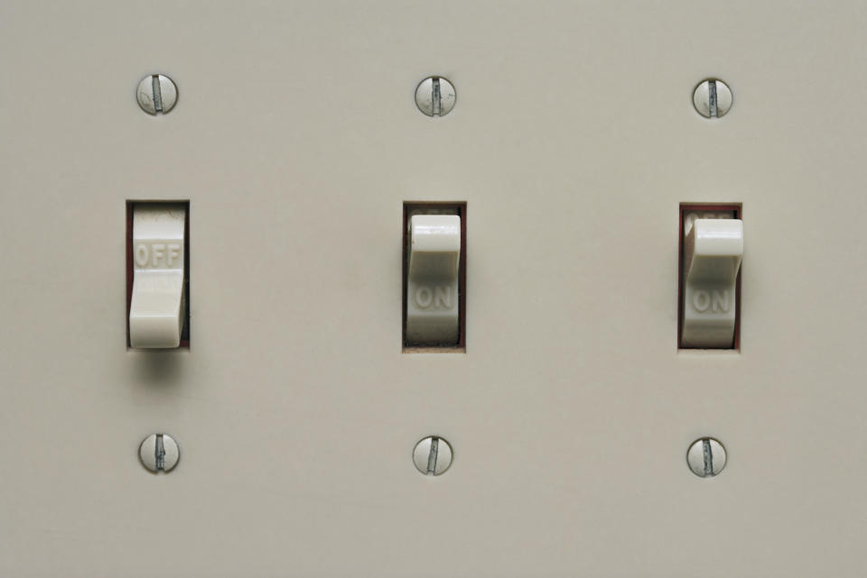 Three light switches on a wall, with the middle switch in the 'ON' position and the others 'OFF'