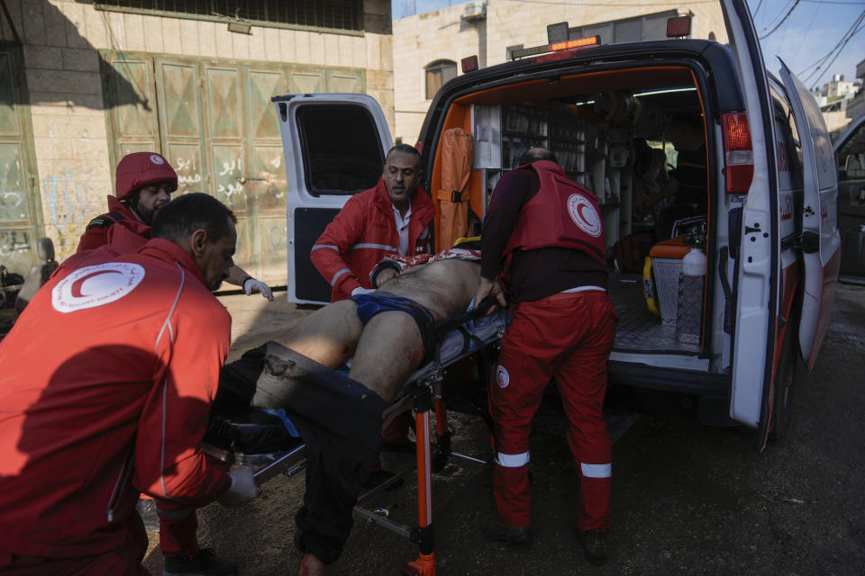 Medics evacuate a wounded Palestinian following an Israeli military raid in Faraa refugee camp, West Bank, Friday, Dec. 8, 2023. The Palestinian Health Ministry says that five Palestinians were killed when Israeli forces raided the camp prompting fighting with local militants. (AP Photo/Majdi Mohammed)