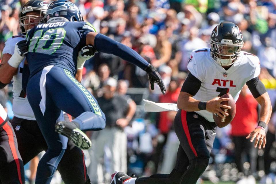 Atlanta Falcons quarterback Marcus Mariota (1) scrambles out of the pocket as Seattle Seahawks linebacker Uchenna Nwosu (10) rushes in during the first quarter of an NFL game on Sunday, Sept. 25, 2022, at Lumen Field in Seattle.